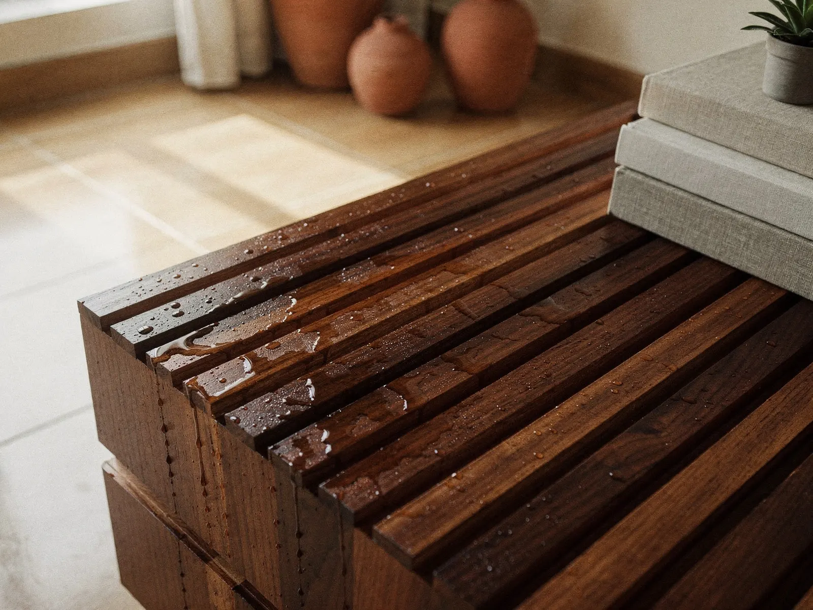 Ripas de cumaru com gotas de água escorrendo, luz lateral fria.